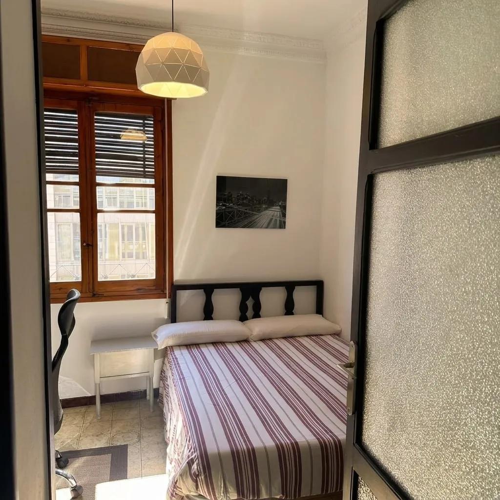 Dormitorio con ventana de madera y puerta de cristal