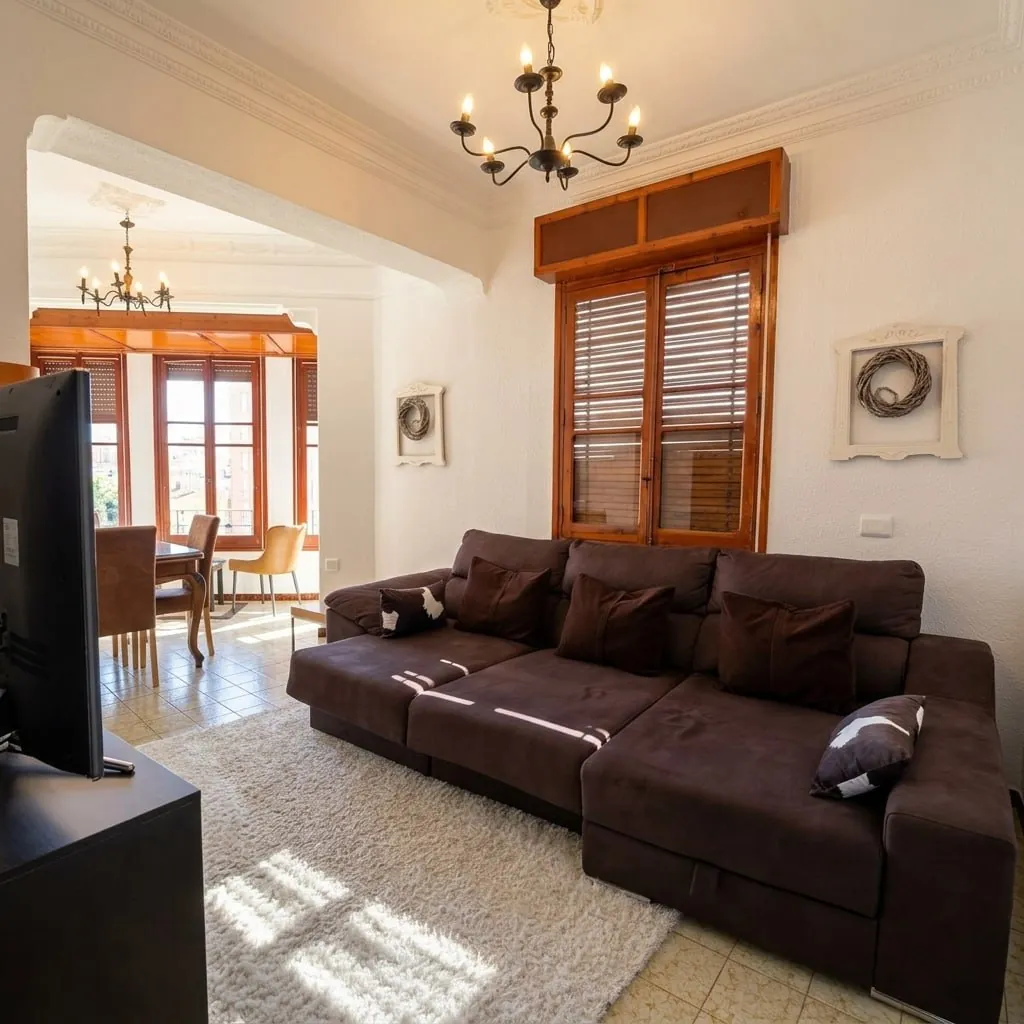 Salón con sofá, comedor al fondo y ventanales
